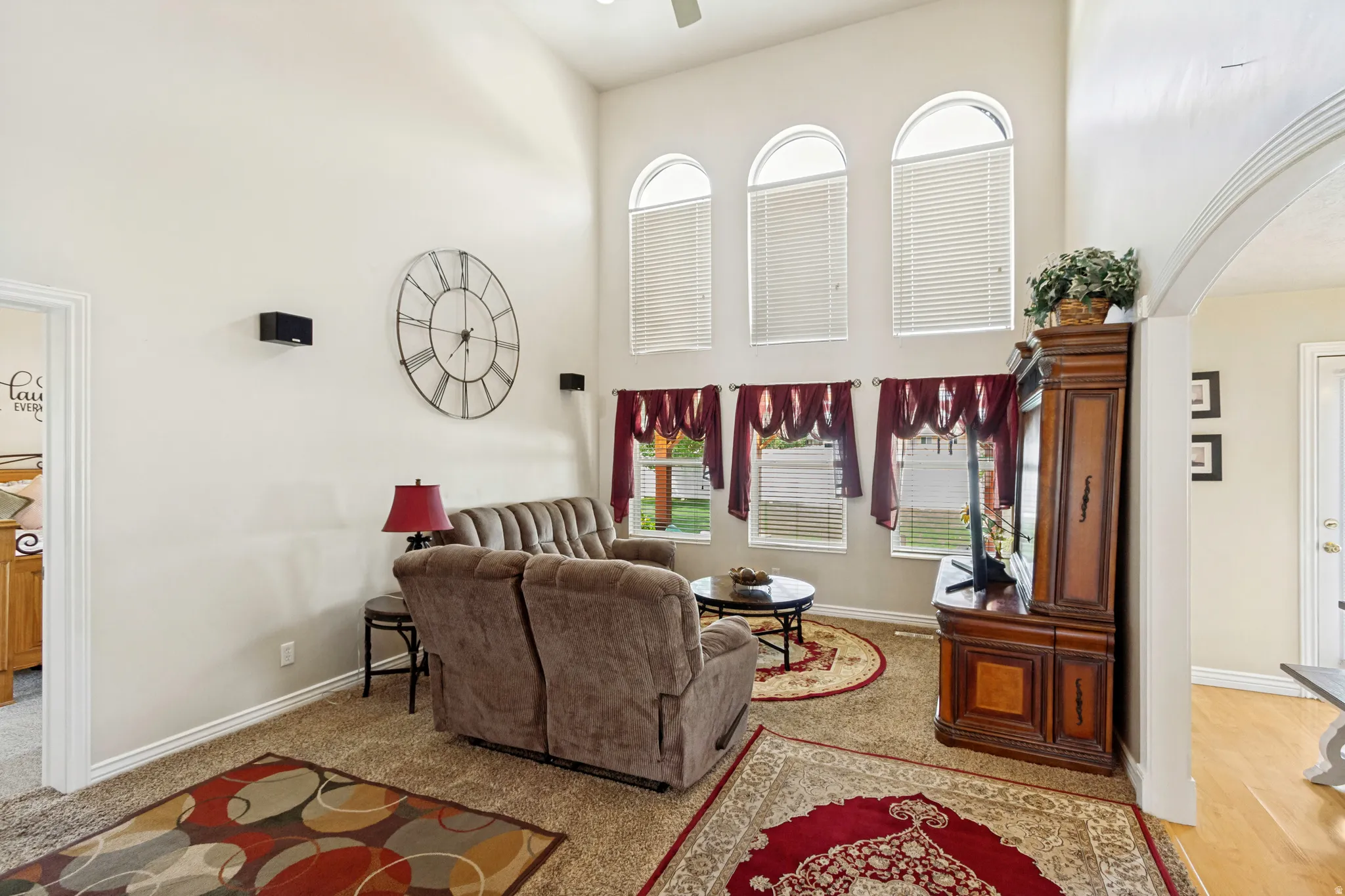 Living area with vaulted ceilings featuring three arched windows and three rectangular windows, all with blinds