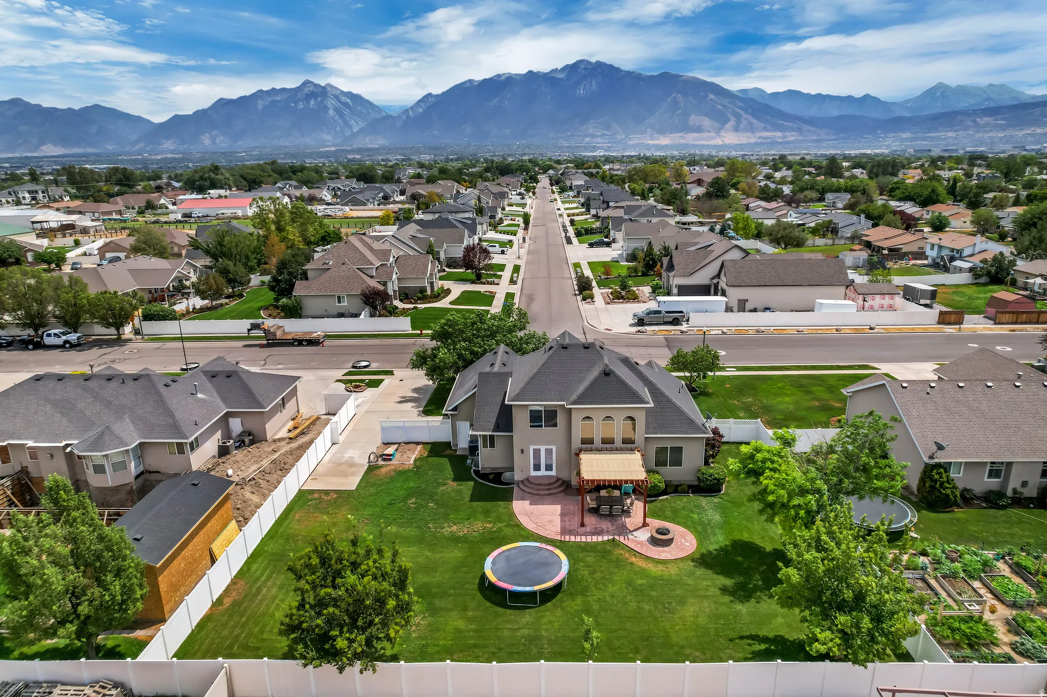 Expansive property featuring a large green lawn, a brick patio with a pergola, and a circular fire pit area
