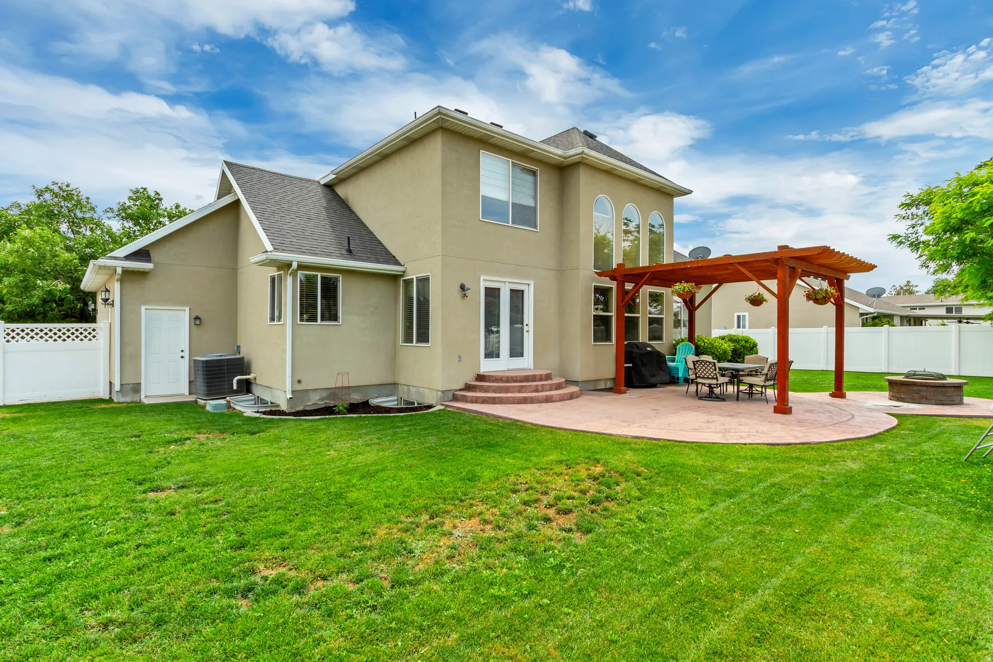 Rear exterior featuring a spacious lawn, a stamped concrete patio, and a wood pergola