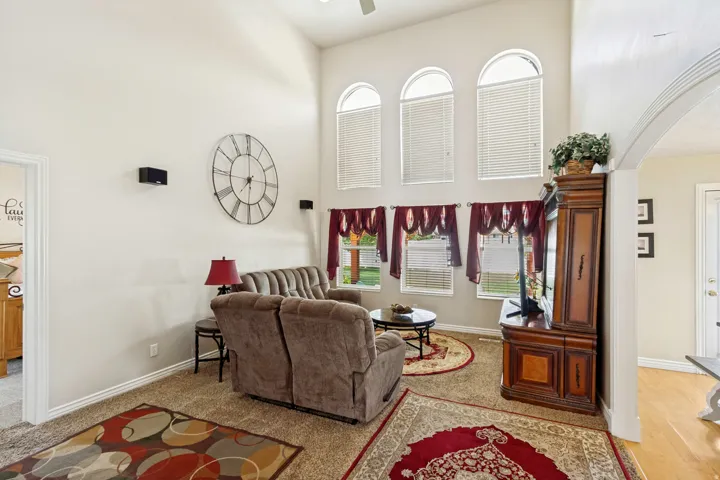 Living area with vaulted ceilings featuring three arched windows and three rectangular windows, all with blinds
