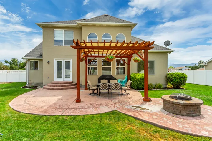 Expansive concrete patio featuring a pergola, built-in fire pit, and French doors