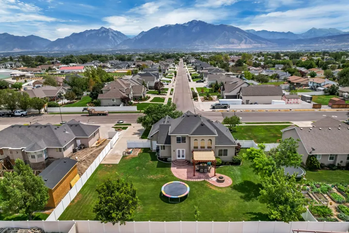Expansive property featuring a large green lawn, a brick patio with a pergola, and a circular fire pit area