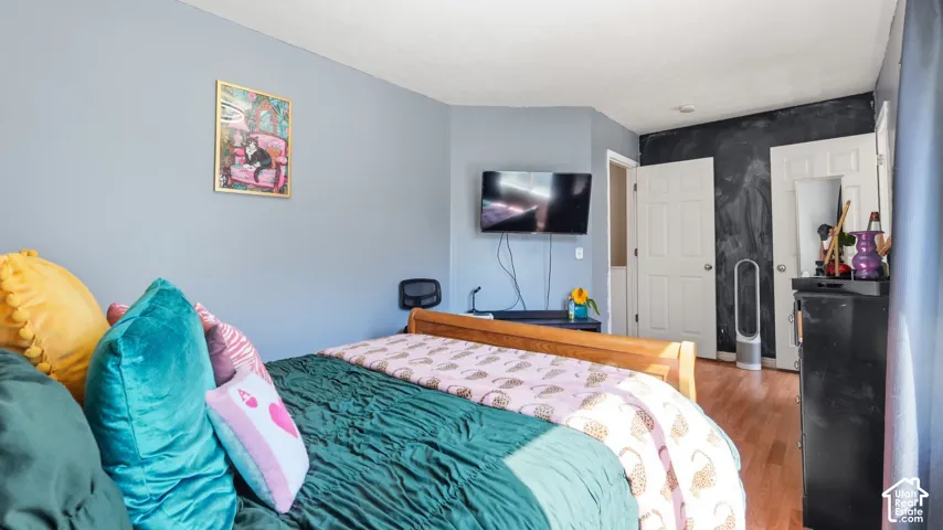 Interior room featuring light blue walls, wood-finish flooring, white paneled doors, and a dark accent wall