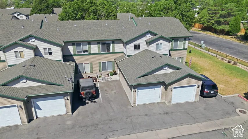 Multi-unit property featuring tan siding with green trim, shingled roofing, and multiple attached garages