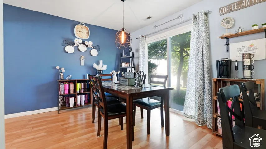 Dining area featuring wood-finish flooring, a contemporary pendant light fixture, and a sliding glass door providing natural light