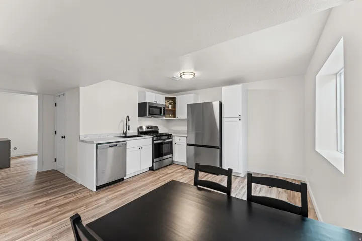 Kitchen featuring stainless steel appliances, white cabinetry, and light-toned wood-finish flooring