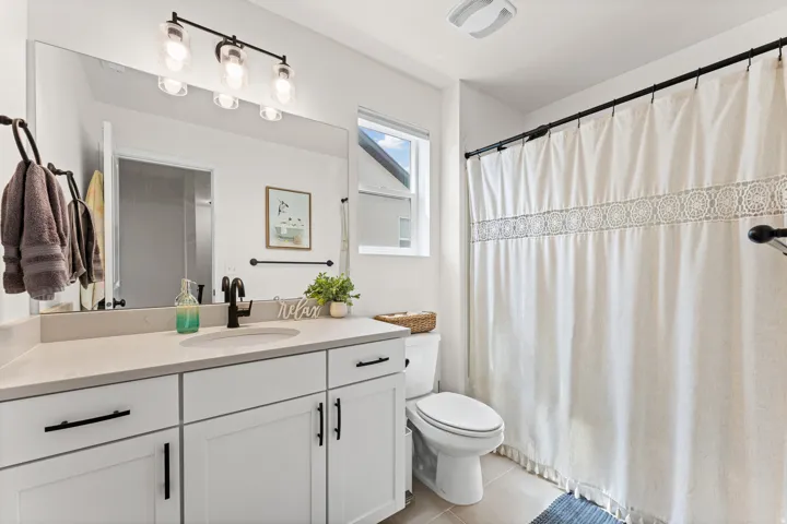 Bathroom featuring a vanity with a light-toned countertop, integrated sink, and white cabinetry with black hardware