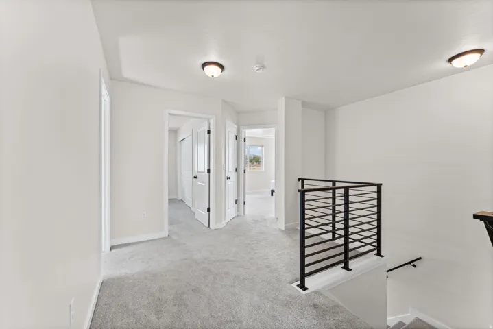 Upper level hallway with neutral wall tones and gray carpet flooring