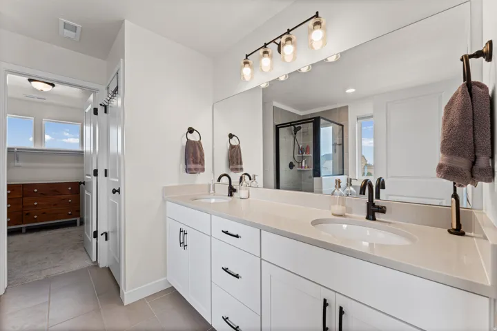 Dual vanity featuring white shaker-style cabinetry, undermount sinks, and dark bronze fixtures
