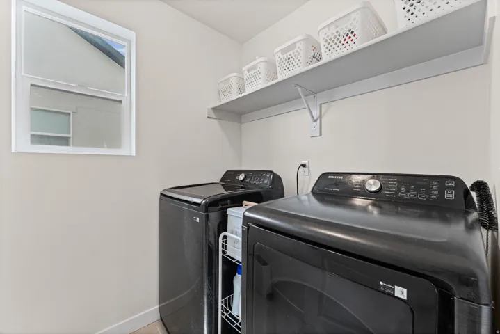 Dedicated laundry area featuring a white window, light neutral wall color, and a built-in shelving unit
