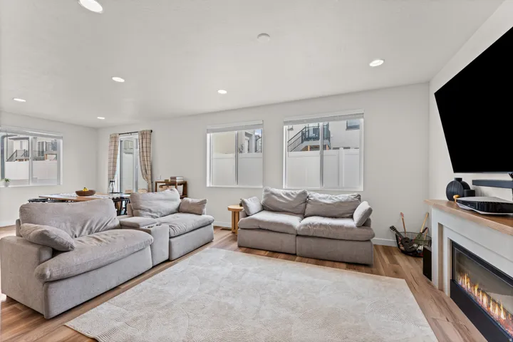 Open-concept living area featuring wood-finish flooring, recessed lighting, and multiple windows
