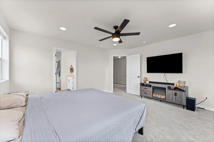 Carpeted interior space featuring a ceiling fan with integrated lighting, recessed lighting, and white walls