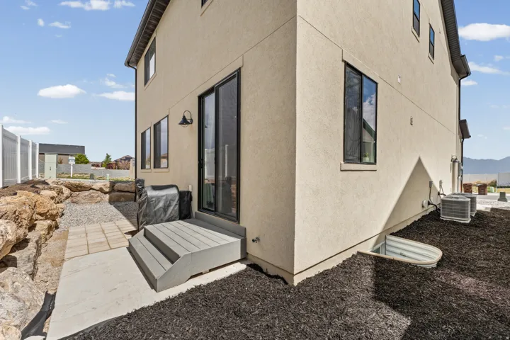 Exterior featuring a stucco finish, black-framed windows, and a black-framed sliding glass door