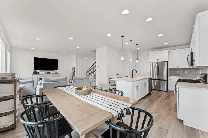 Open-concept living space featuring wood-finish flooring, recessed lighting, and a modern kitchen with white cabinetry and stainless steel appliances