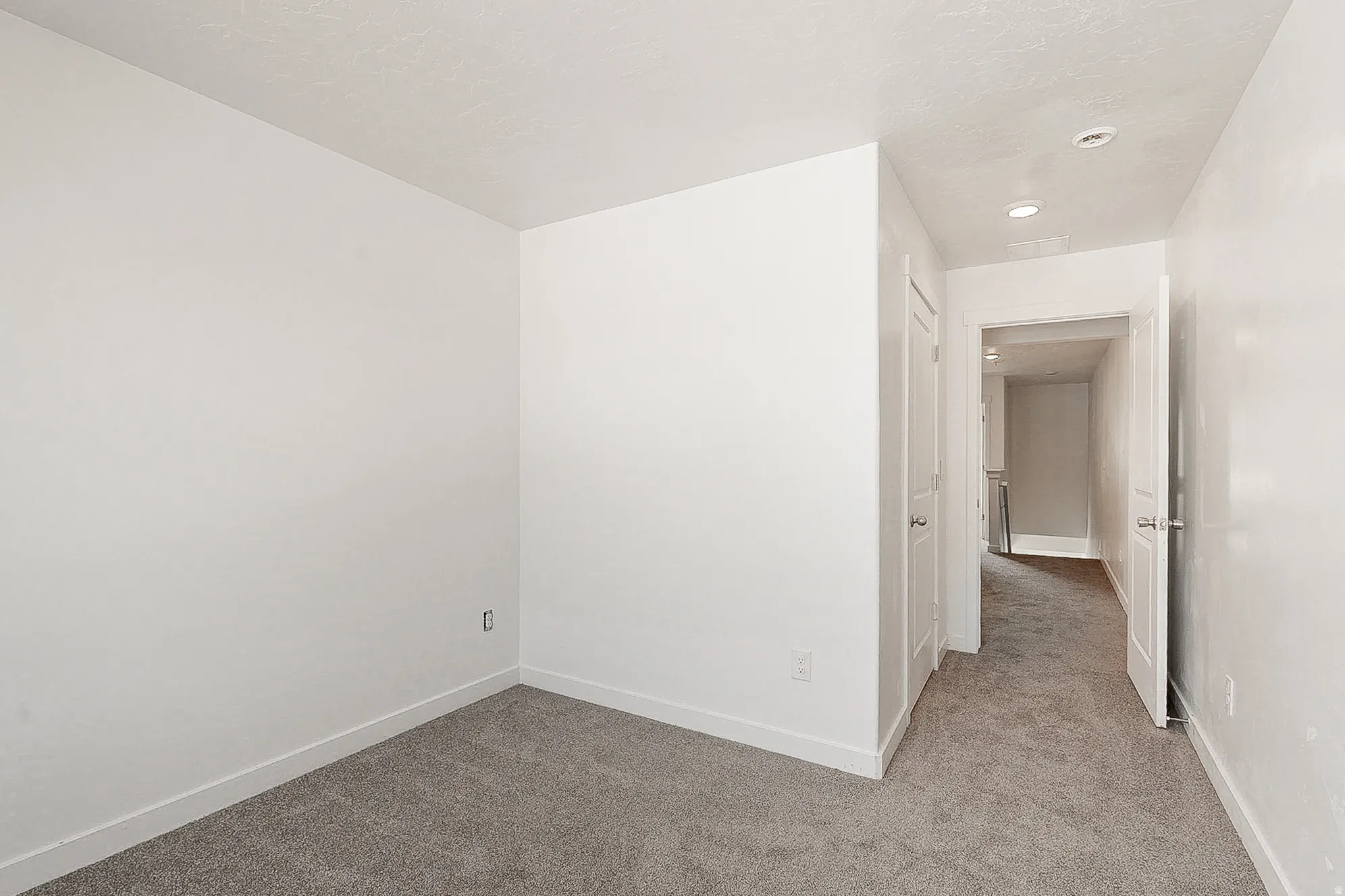 Spacious bedroom featuring neutral walls, plush carpet flooring, and recessed ceiling lighting