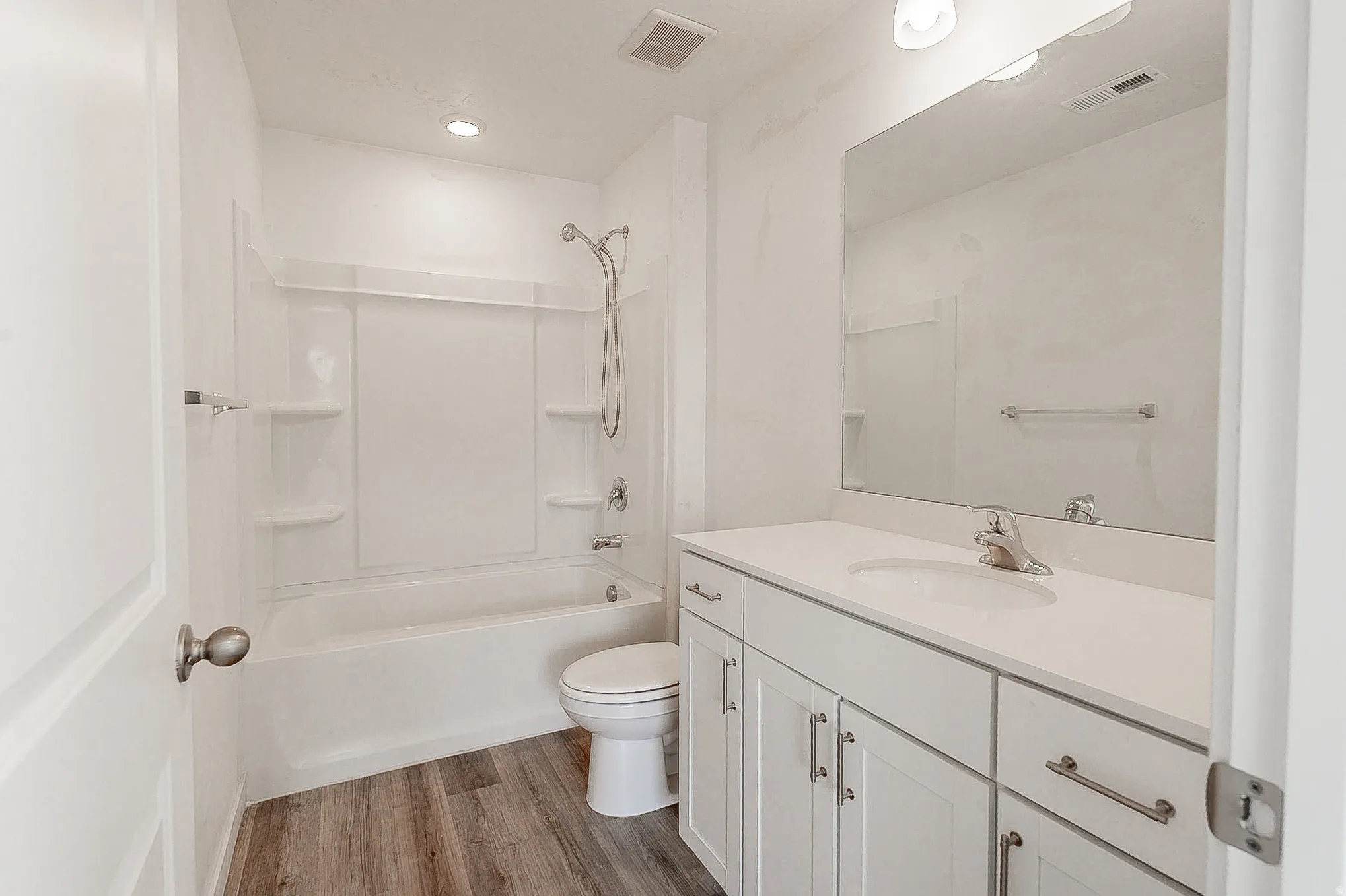 Bathroom featuring a single vanity with white cabinetry, integrated sink, and full-width mirror