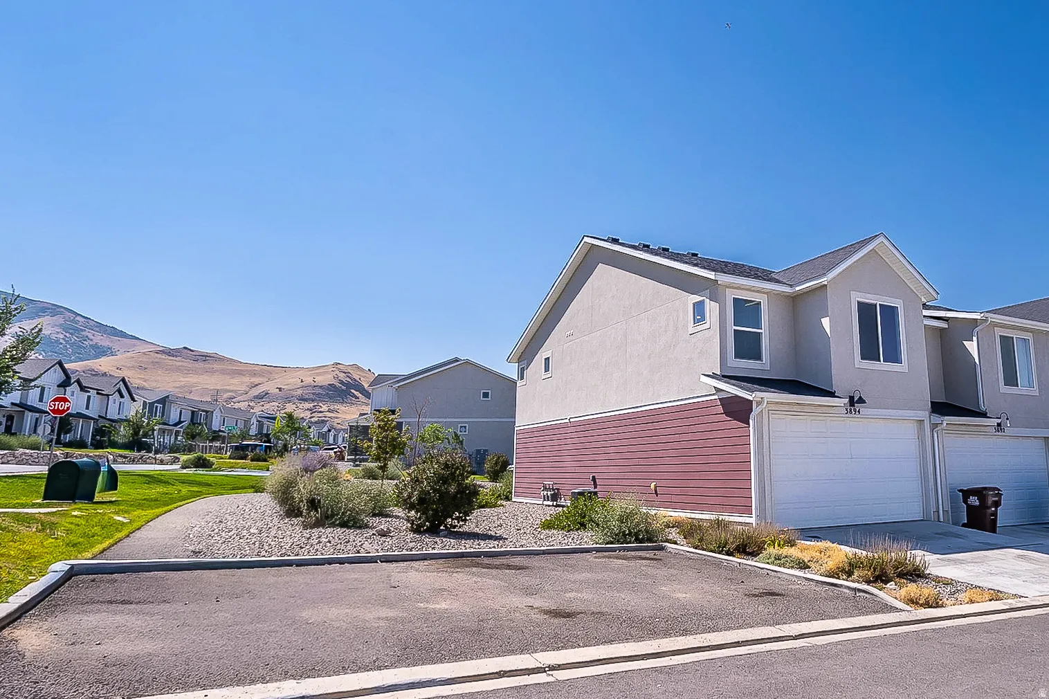 Two-story townhome featuring a neutral stucco exterior and red horizontal siding