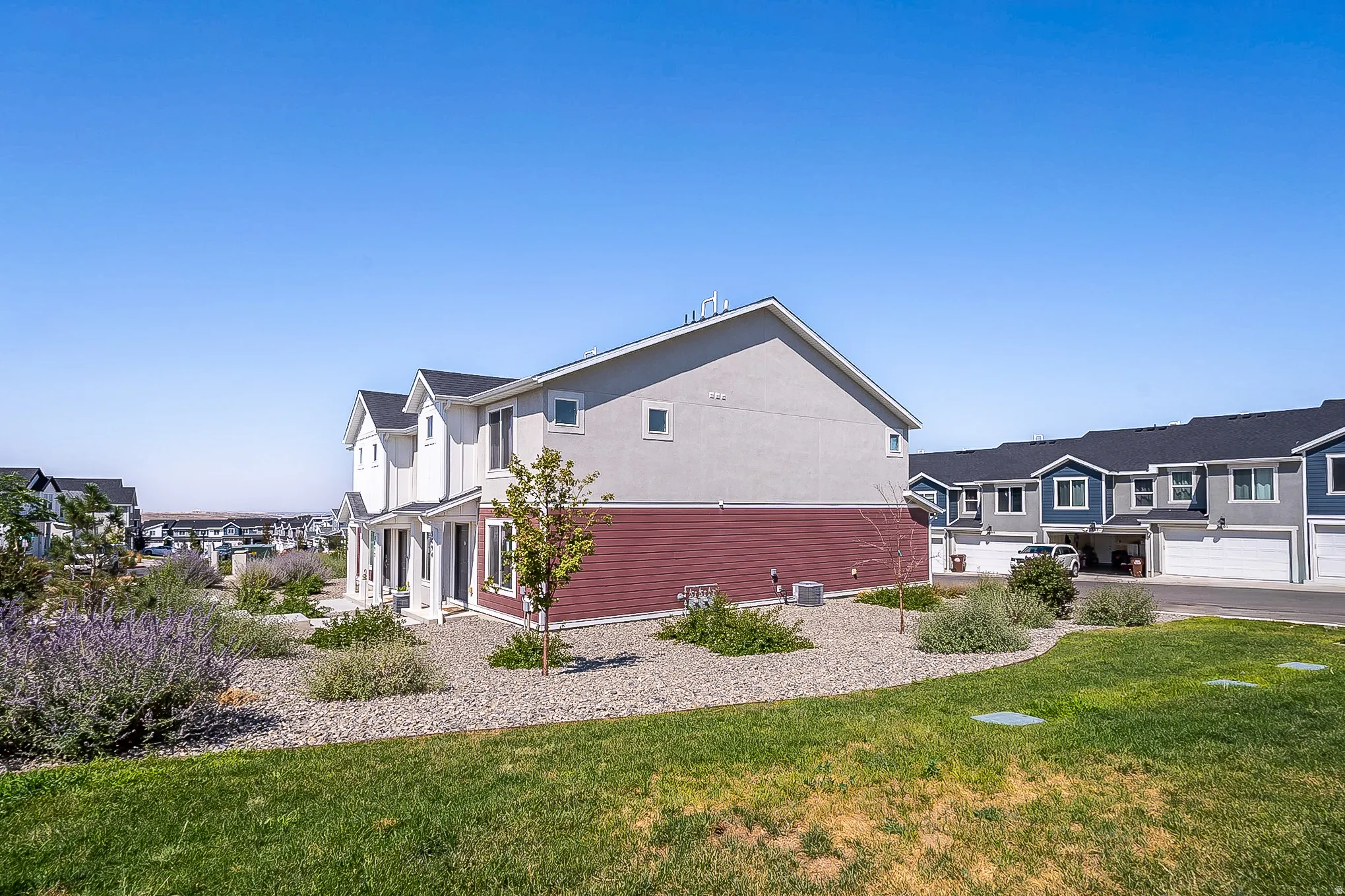 Two-story property featuring light gray stucco and red siding