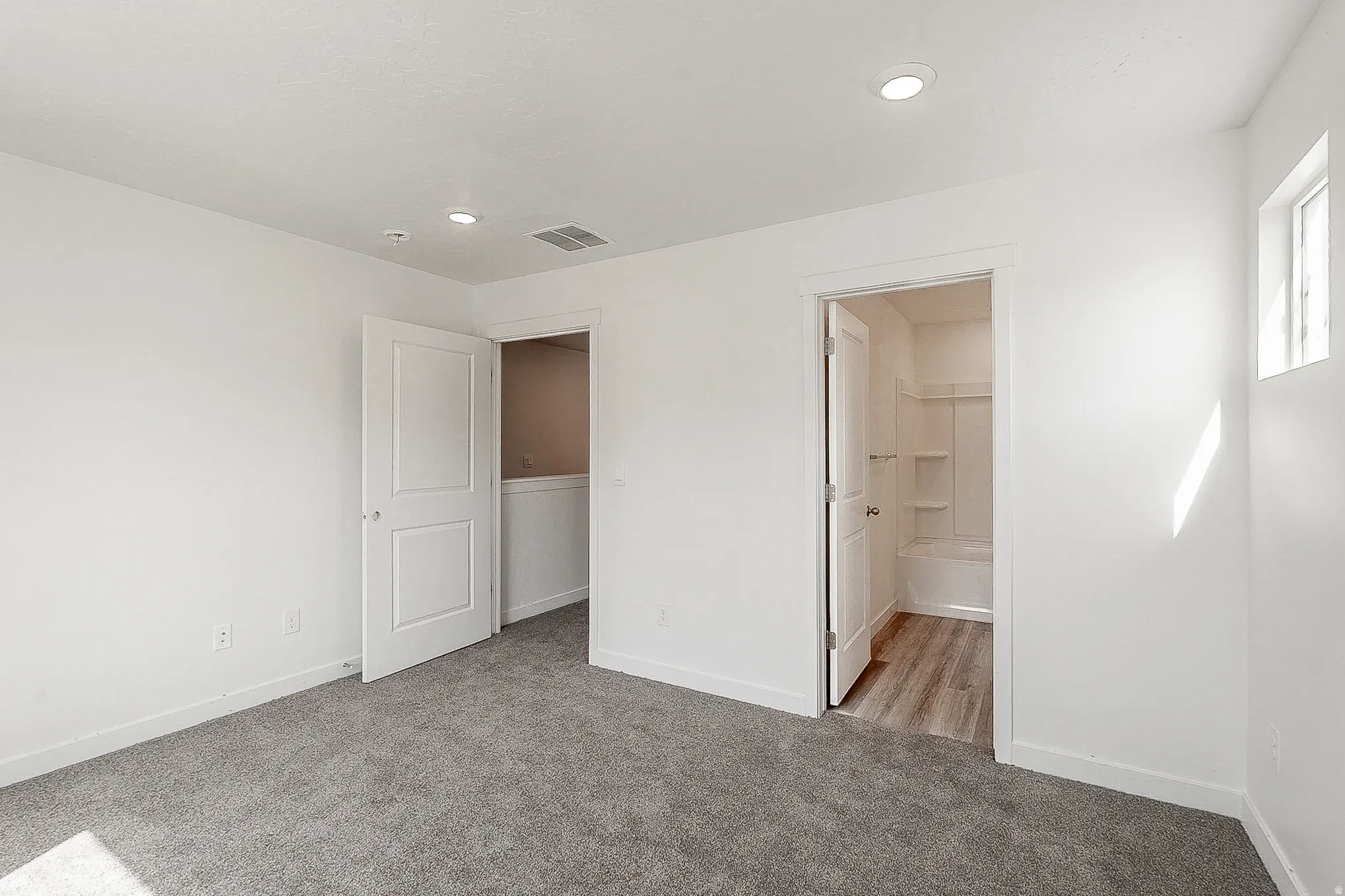 Spacious bedroom with plush carpeting and abundant natural light from transom window
