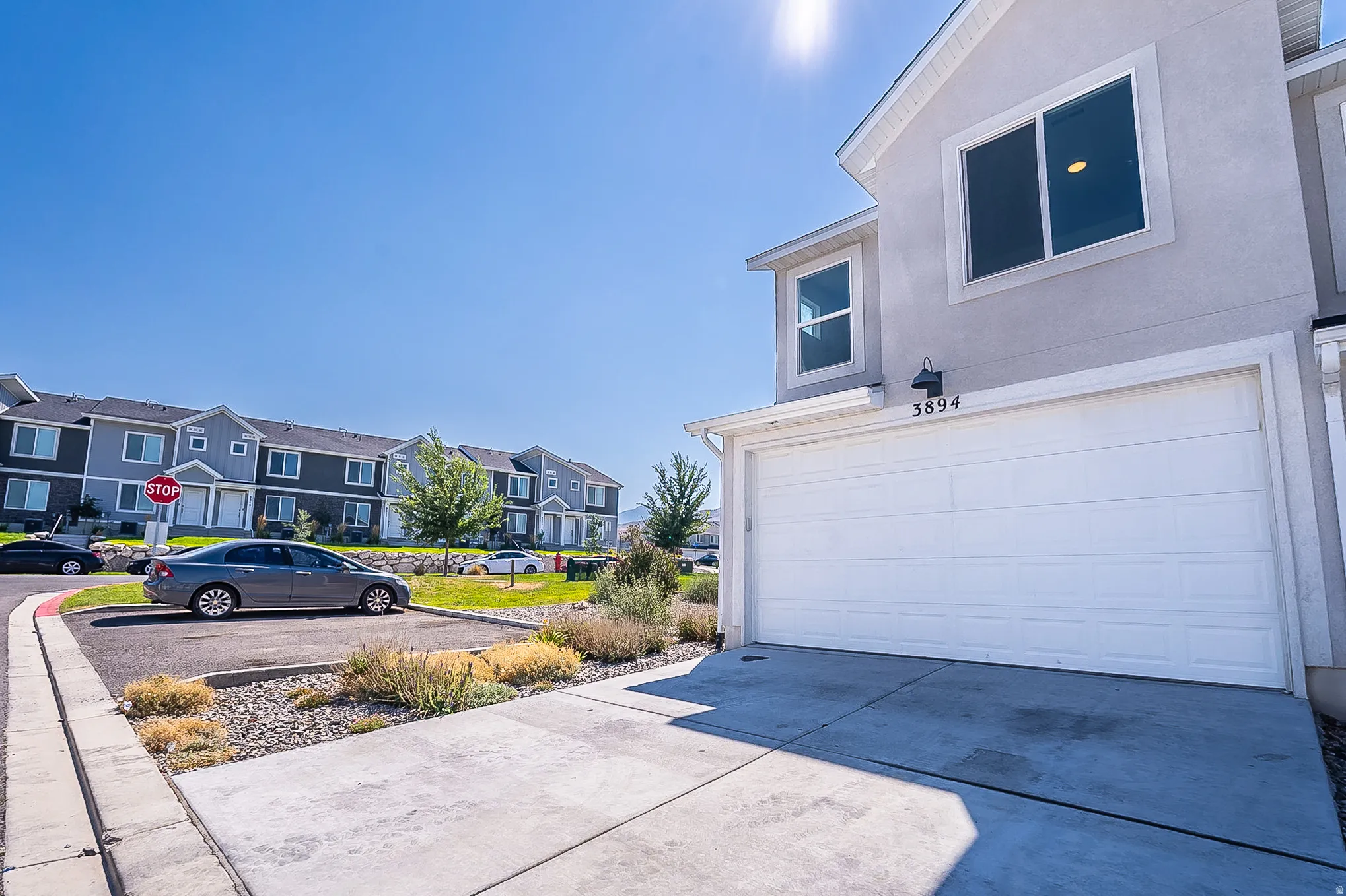 Modern two-story residence featuring a spacious three-car garage with white paneled doors, wide concrete driveway, and clean architectural lines