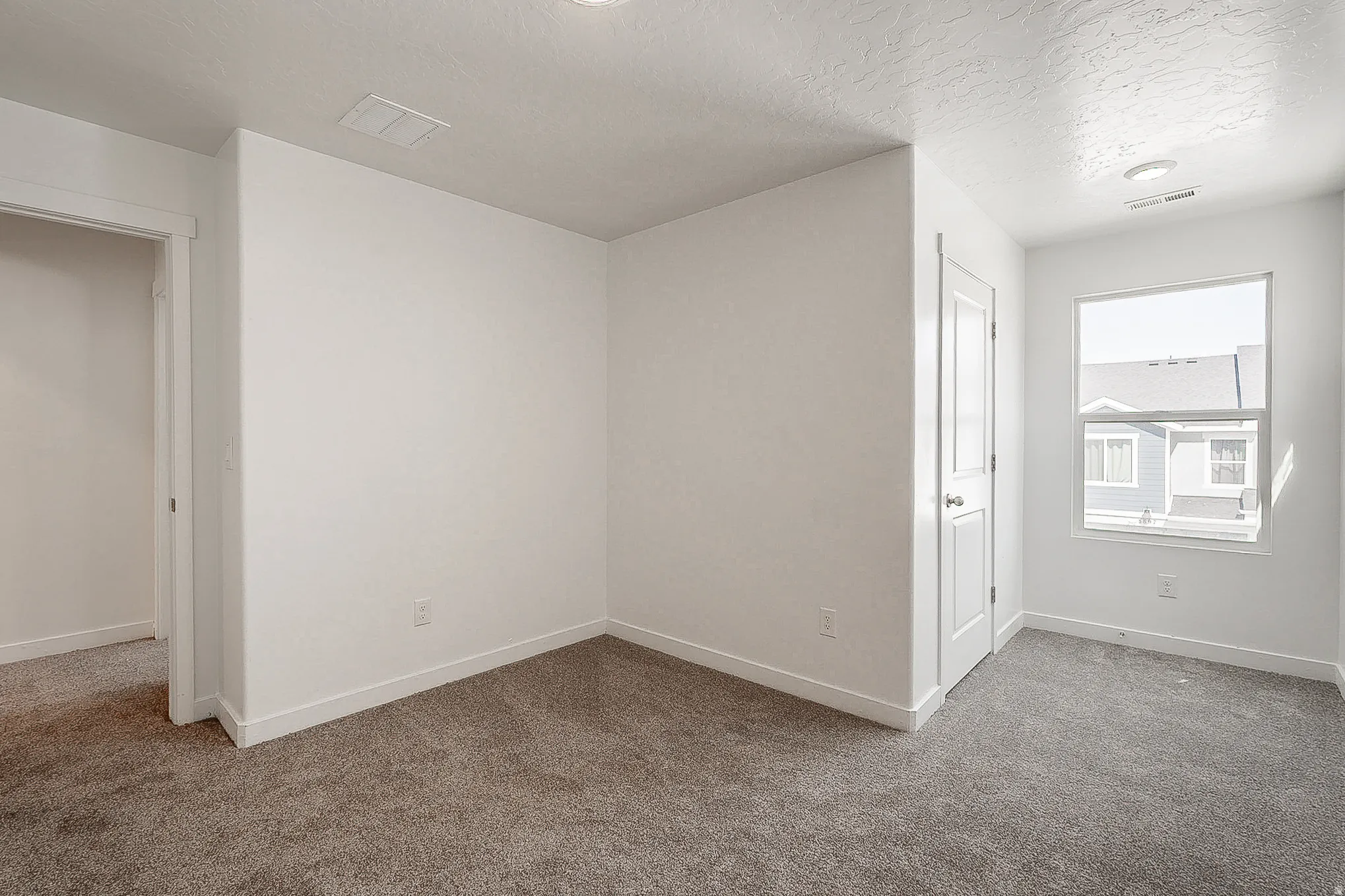 Bright, open bedroom featuring neutral wall finishes, recessed ceiling lighting, and plush carpeting