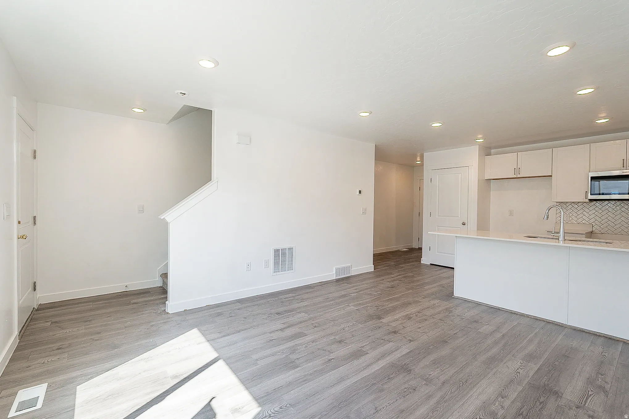 Spacious open-concept interior featuring light wood-finish flooring and recessed lighting