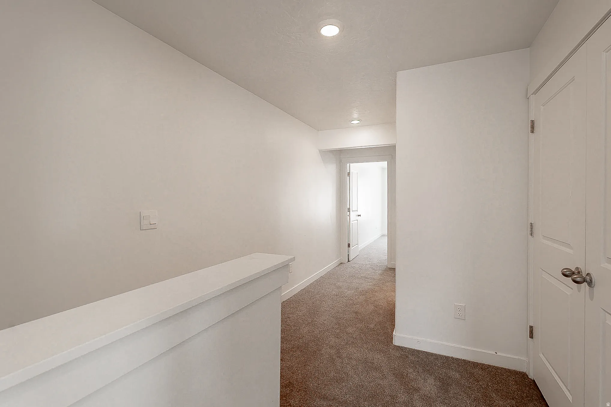 Hallway featuring recessed lighting, light neutral paint, white trim, and brown carpet flooring