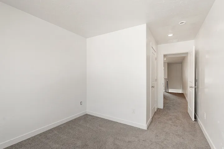 Spacious bedroom featuring neutral walls, plush carpet flooring, and recessed ceiling lighting