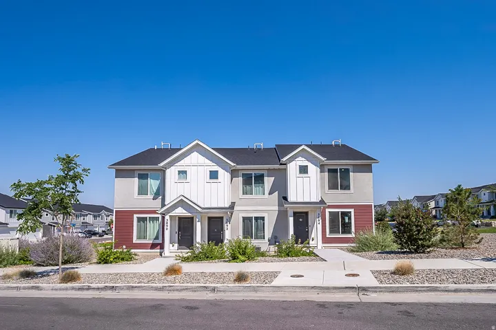 Modern multi-unit residential property featuring a striking two-tone exterior with white and burgundy fiber cement siding, peaked rooflines with architectural gables, and dark asphalt shingle roofing