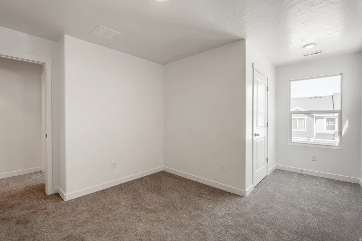 Bright, open bedroom featuring neutral wall finishes, recessed ceiling lighting, and plush carpeting