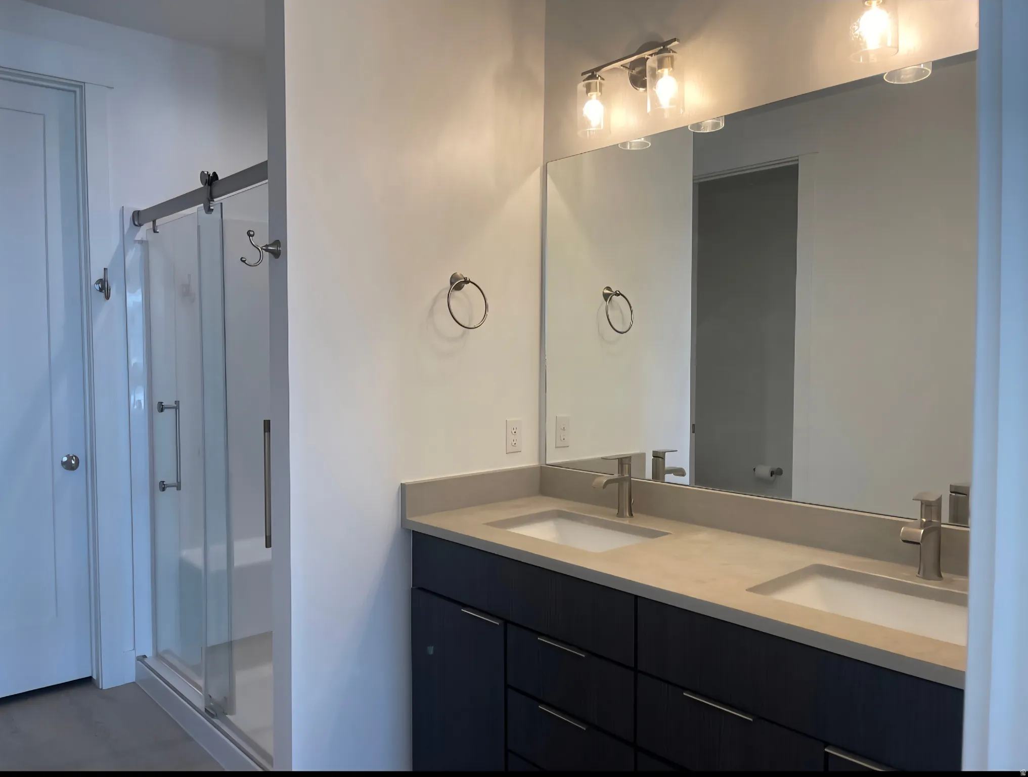 Modern primary bathroom featuring a dual-sink vanity with a light-finish countertop, black cabinetry with multiple drawers, and polished chrome fixtures