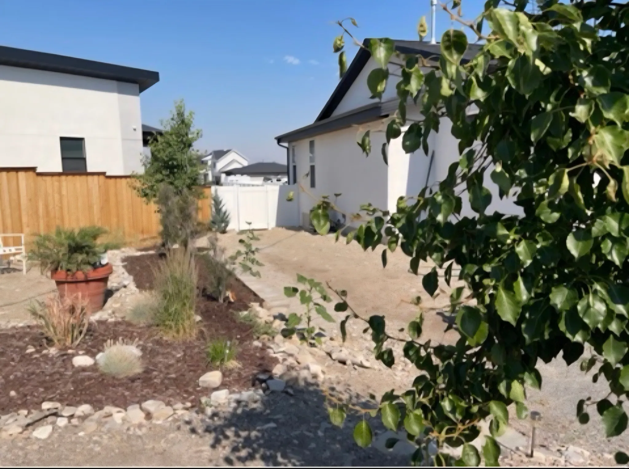 Landscaped side yard featuring a wood privacy fence, decorative rock, and planted garden beds