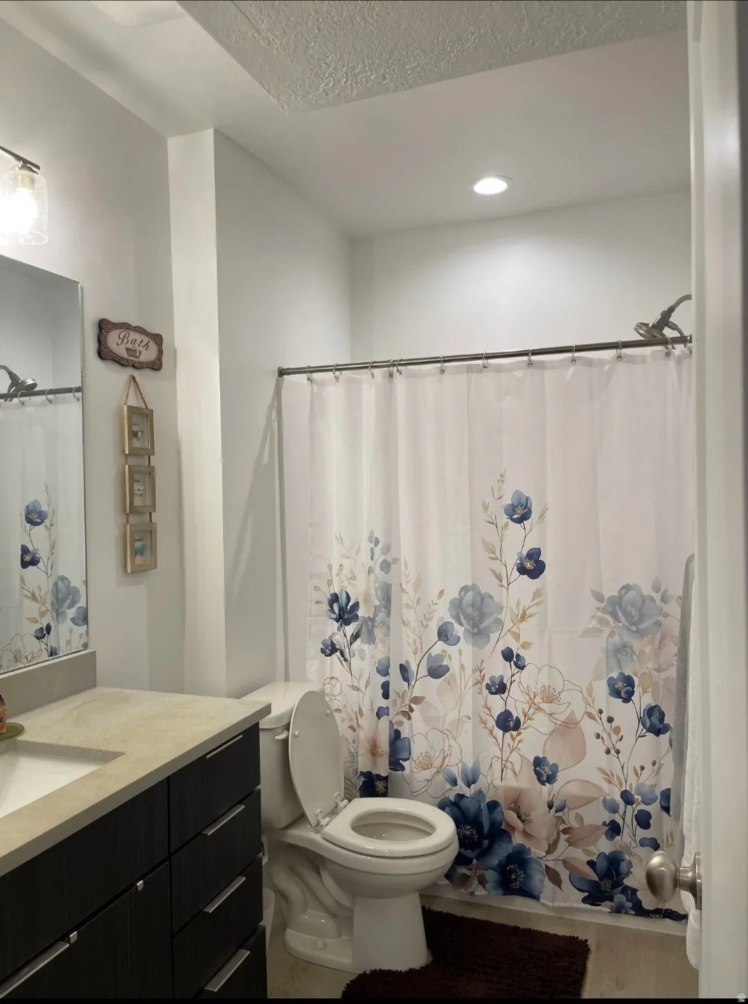 Modern bathroom featuring a dark vanity with ample storage, light quartz countertop, and recessed ceiling lighting