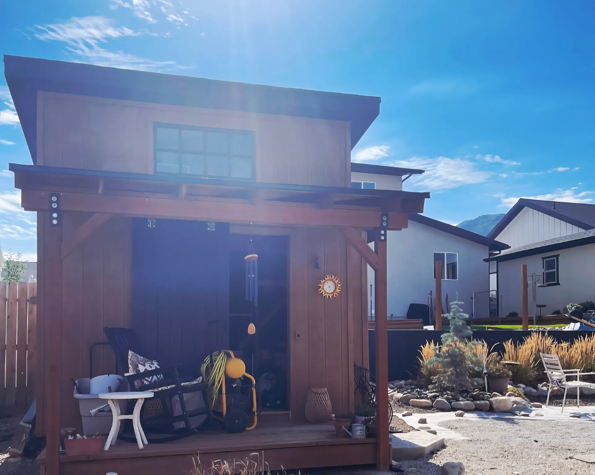 Modern backyard shed featuring a custom wood-clad structure with expansive covered porch, large operable windows, and integrated outdoor living space
