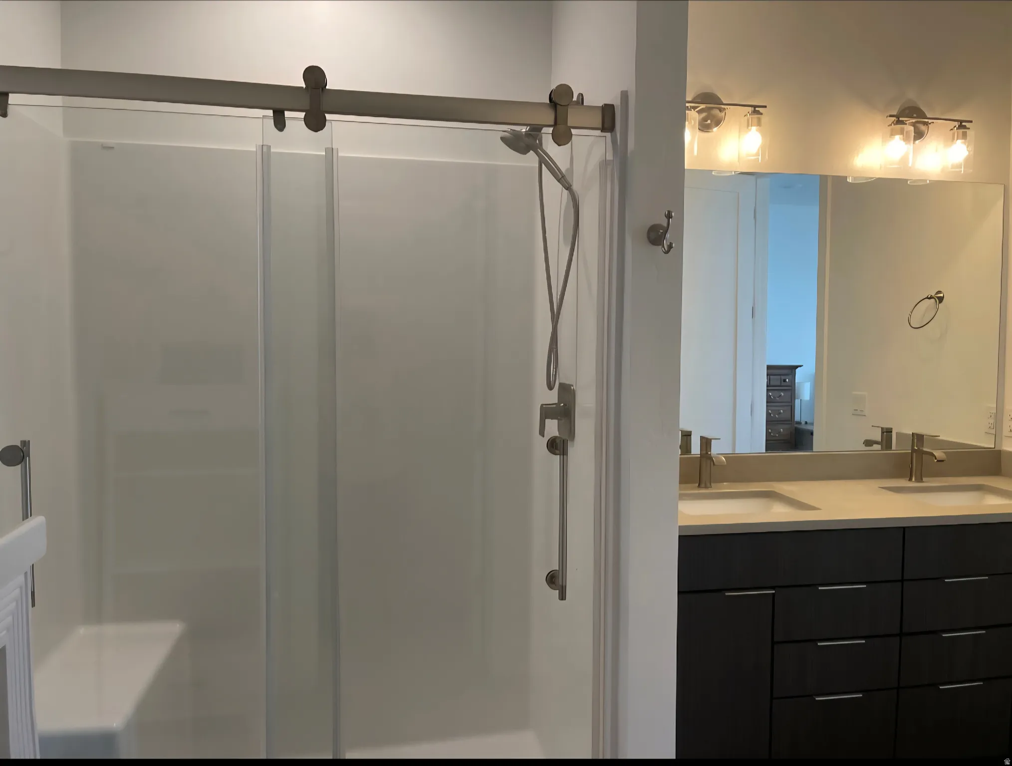 Contemporary bathroom featuring a dual vanity with dark wood-finish cabinetry, brushed nickel hardware, and a light-toned countertop