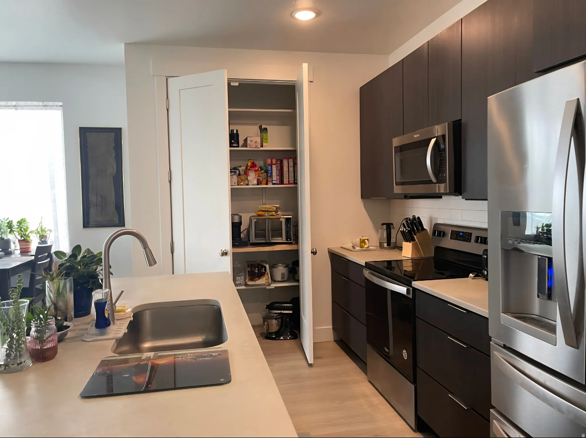 Modern kitchen featuring stainless steel appliances, dark wood-finish cabinetry, light Caesarstone quartz countertops, and a white subway tile backsplash