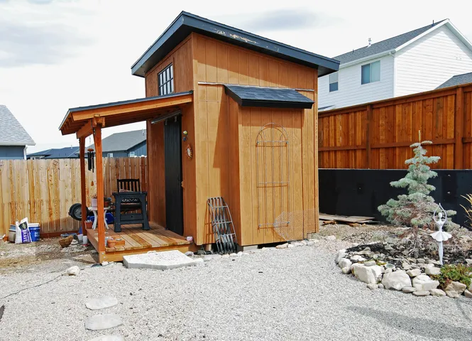 Custom wood-clad backyard structure featuring a covered porch with timber framing, pitched roof design, and vertical wood siding
