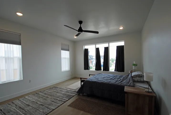Recessed lighting, ceiling fan, multiple windows with blinds, and wood-finish flooring