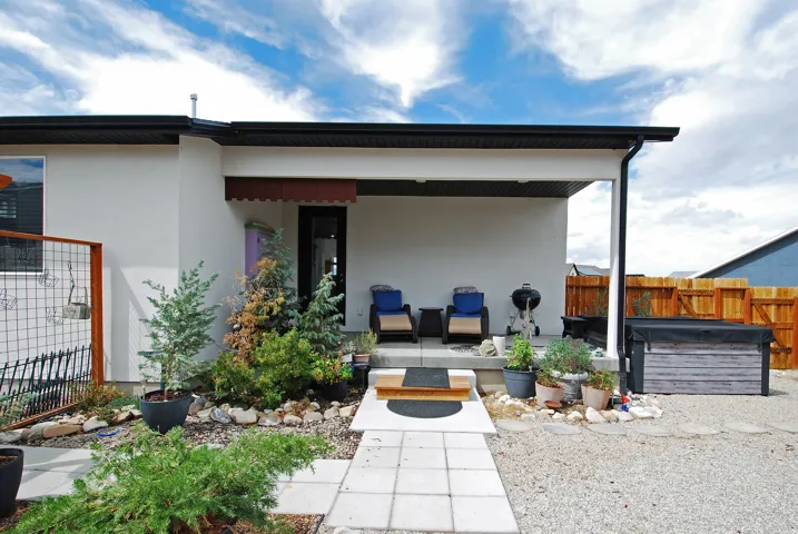 Covered patio with concrete steps, a wood-slat hot tub surround, and a natural wood privacy fence