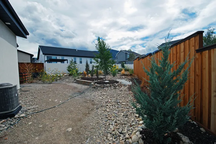 Wood-paneled fencing, gravel ground cover, and landscape plantings