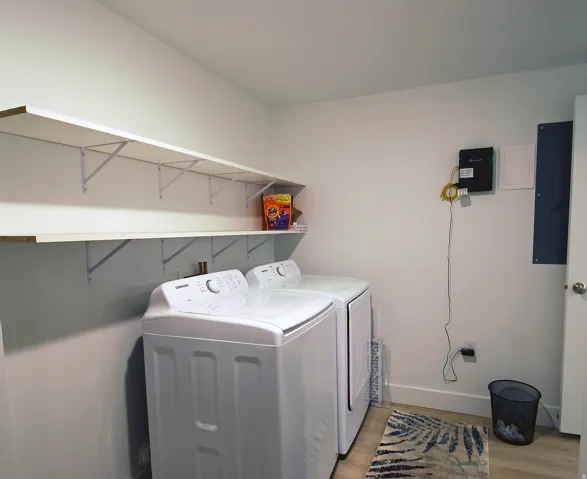 White walls with dual floating shelves, light wood-finish flooring, and built-in appliances