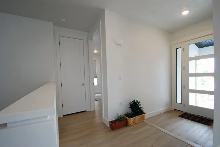 Laminate wood-finish flooring, recessed lighting, and a modern entry door with multiple glass panels