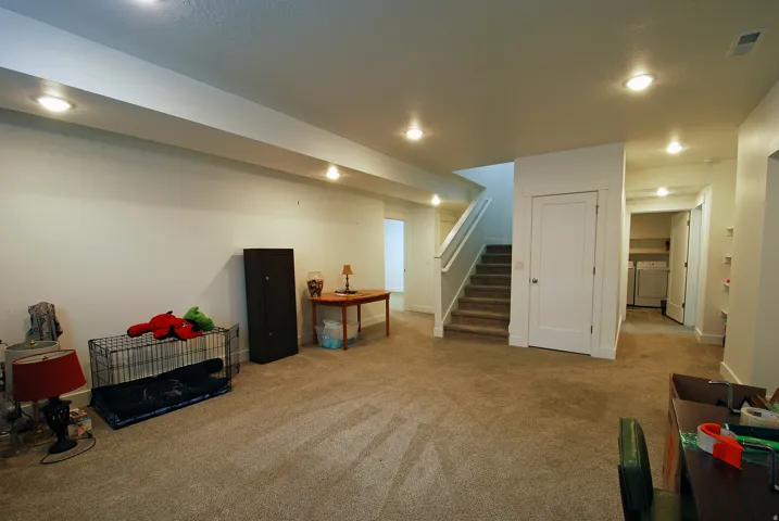 Carpeted lower level with recessed lighting, staircase with white railings, and white interior doors