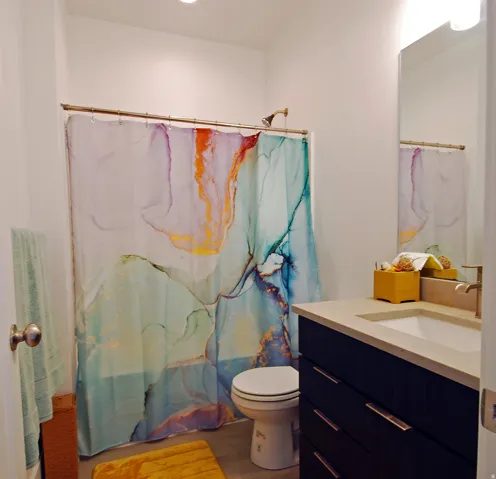 Bathroom featuring a shower-tub combination, single vanity with integrated sink, and a light-toned countertop