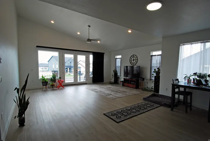 Vaulted ceiling, recessed lighting, ceiling fan, wood-finish flooring, and French doors leading to a balcony