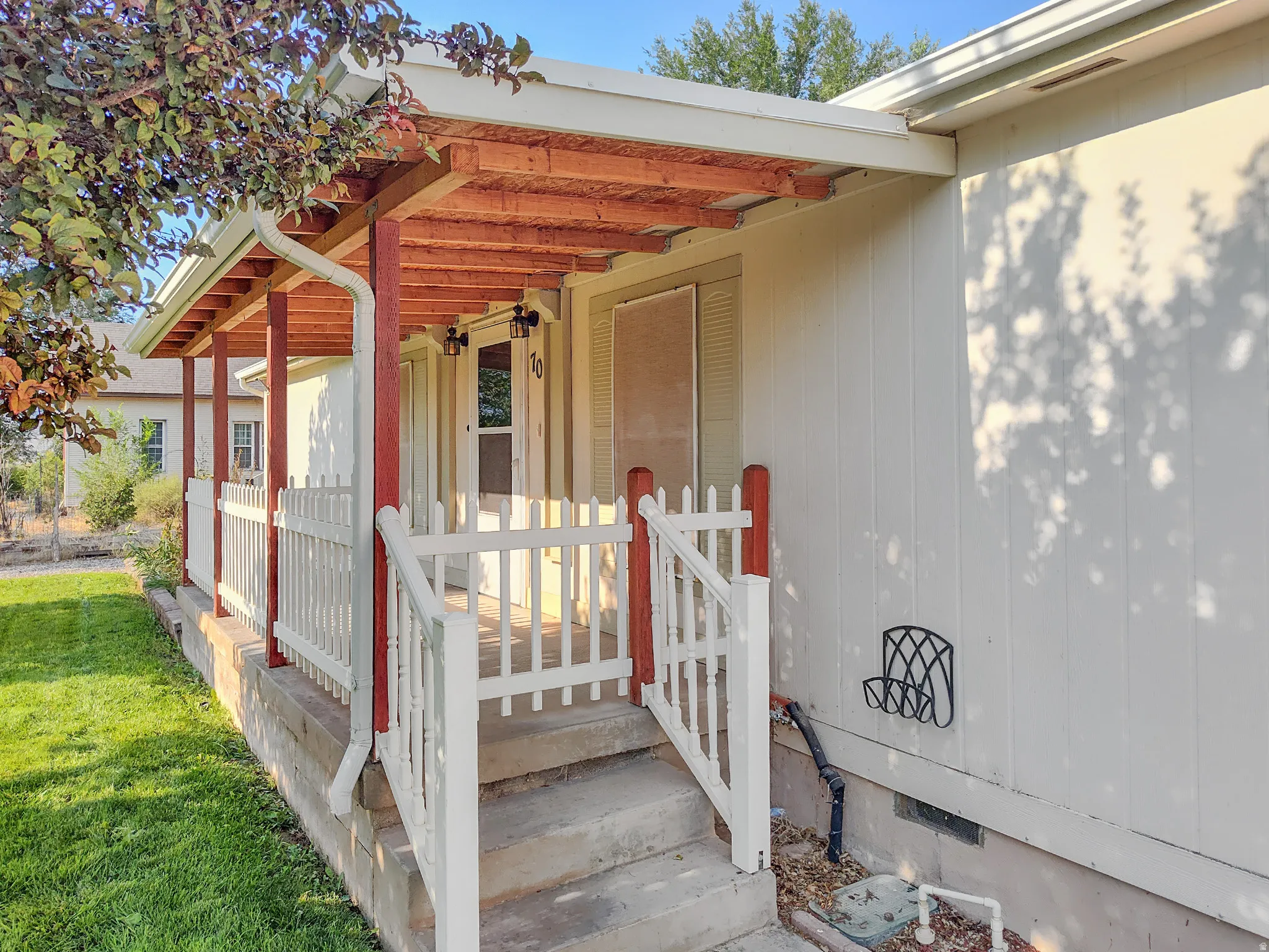 Charming covered entry featuring a wood-beam pergola with white picket railings and gated access