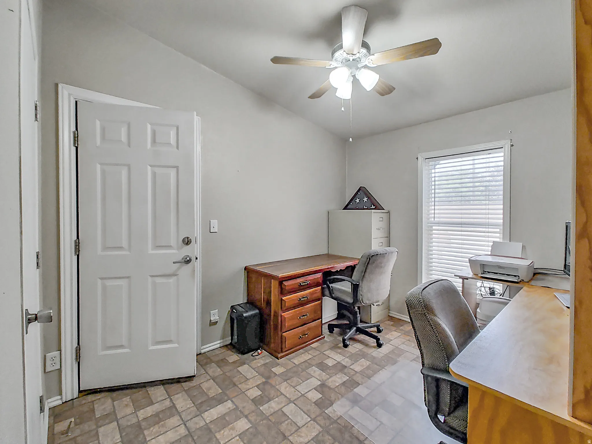 Bedroom or home office with neutral wall paint and patterned tile flooring