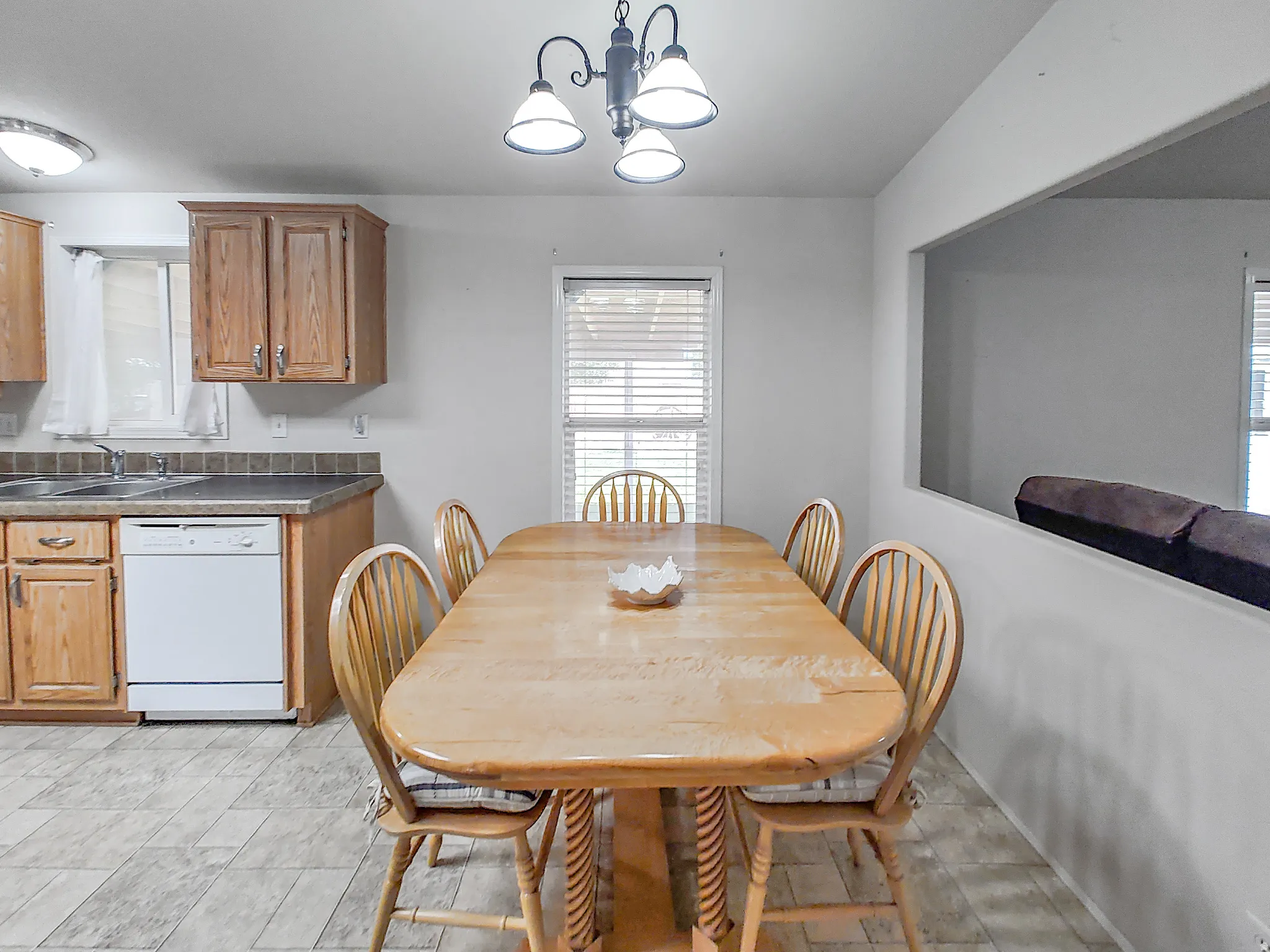 Dining area featuring wood-finish flooring, a contemporary chandelier, and an open pass-through window to an adjacent room