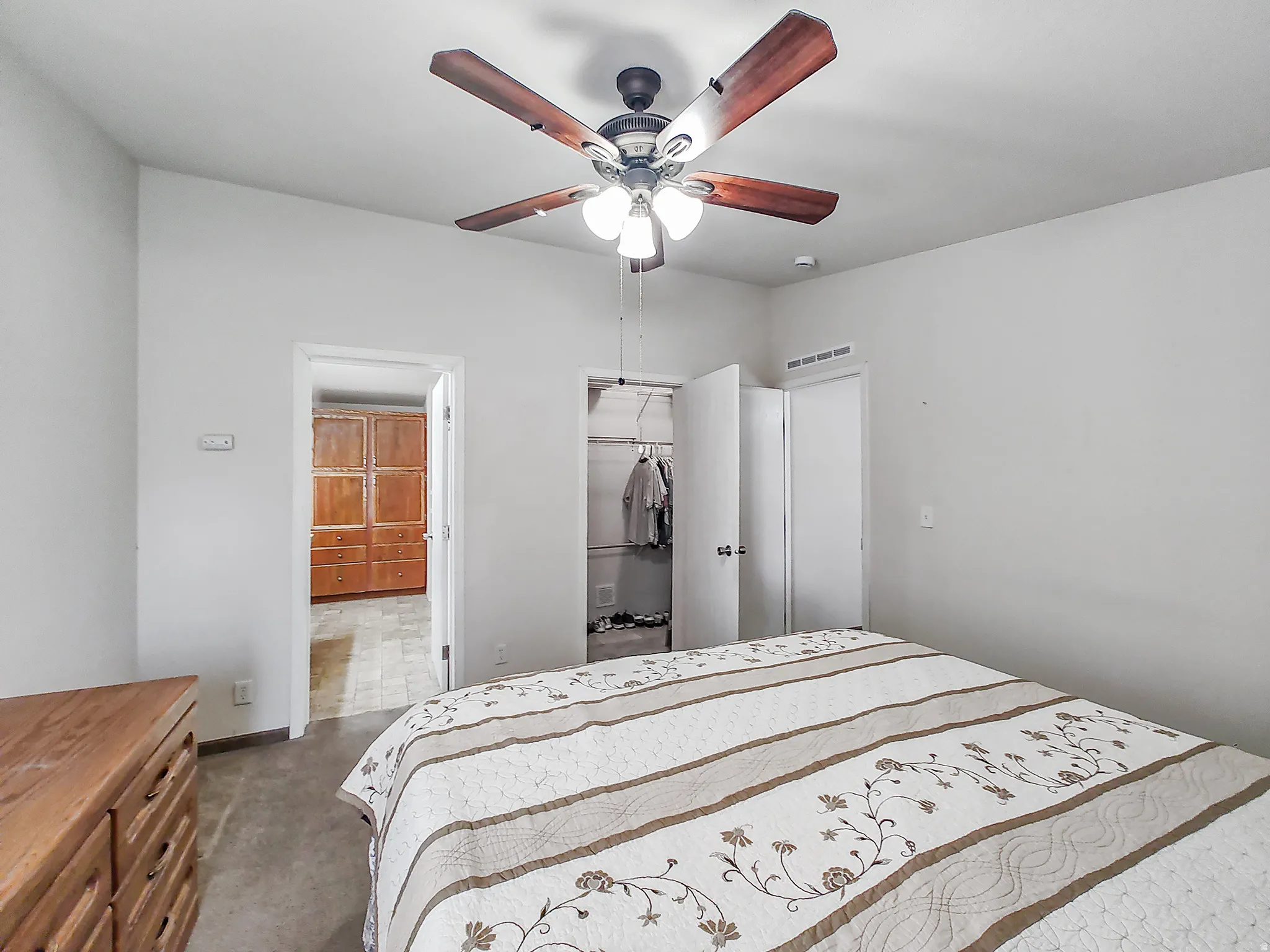 Spacious bedroom featuring wood-finish flooring, ceiling fan with integrated lighting, and generous closet storage