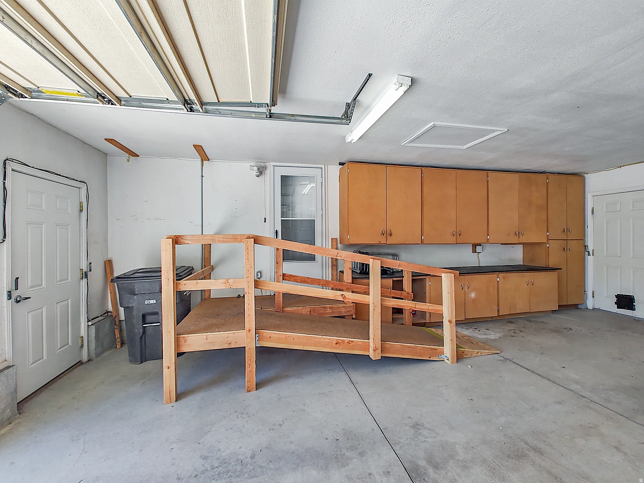 Garage featuring extensive cabinetry, countertop workspace, and concrete flooring